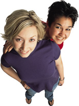 Picture of two very happy lesbian girlfriends, one is of European descent with blonde hair and the other is Latina with dark brown hair